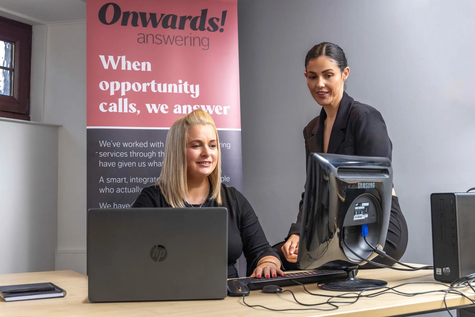 Business owner reviewing growth plans while a receptionist with a headset answers calls